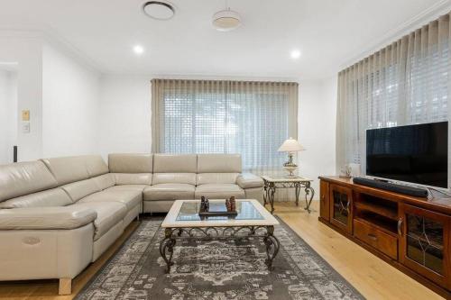 a living room with a couch and a flat screen tv at Coastal House in Gold Coast