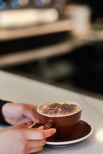 a person holding a cup of coffee on a table at Swiss-Belhotel Napier in Napier
