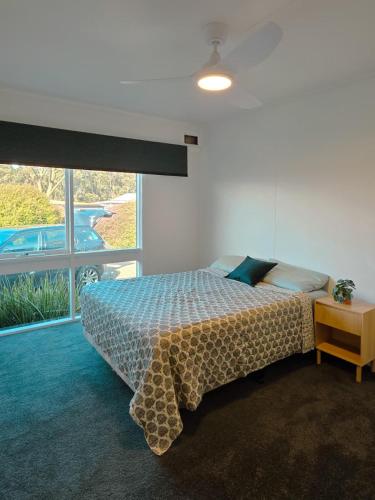 a bedroom with a bed and a large window at Sitara Cottage in Yanakie