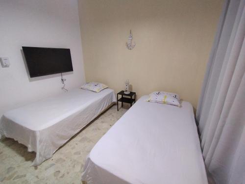 two beds in a room with a tv on the wall at Double bed room in Santo Domingo