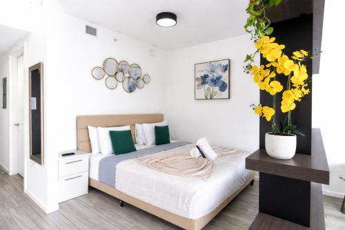a bedroom with a bed and a vase with yellow flowers at Downtown Skyline Heights with Stunning Ocean View in Miami