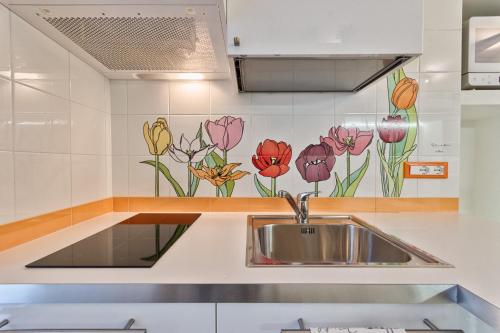a kitchen with a sink and flowers painted on the wall at LittleAndCosy in Turin