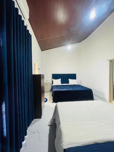 a bedroom with two beds and blue curtains at Golden Paradise Transit Hotel in Katunayaka