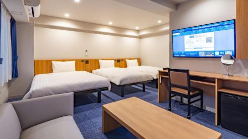 a hotel room with two beds and a large screen at Toyoko Inn Sendai Higashi-guchi No.1 in Sendai