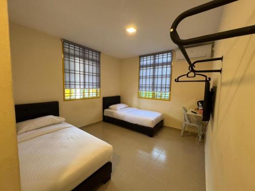 a bedroom with two beds and a desk and two windows at Skudai Sojourn in Skudai
