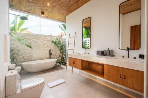 a bathroom with a tub and a toilet and a sink at Sapta Cemagi - Villa Deluna in Cemagi