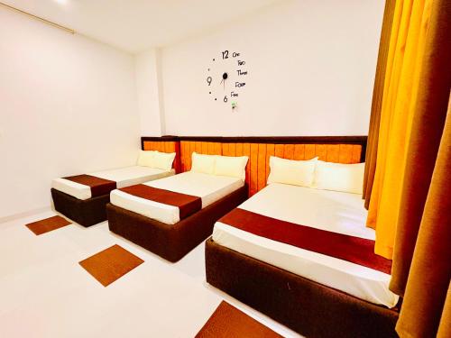a room with two beds and a clock on the wall at Dreamy Homestay in Anuradhapura