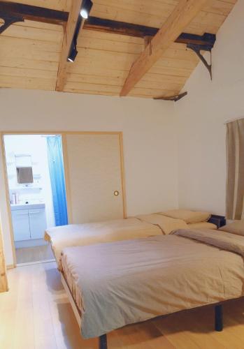 two beds in a room with wooden ceilings at 大阪小林民宿開啟您的夢幻之旅 in Osaka
