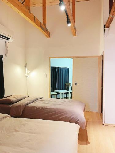 two beds in a bedroom with a table and a window at 大阪小林民宿開啟您的夢幻之旅 in Osaka