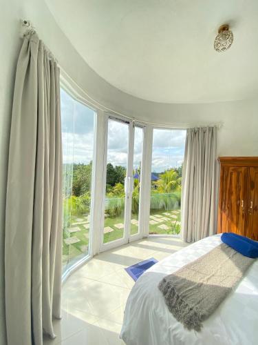 a bedroom with a bed and a large window at De Silaa House & Pool in Bangli