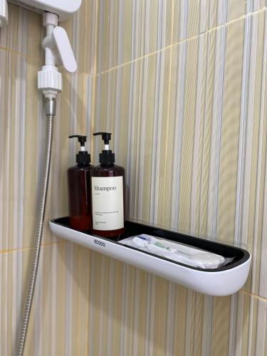 a bathroom shelf with two bottles of soap and a blow dryer at De Silaa House & Pool in Bangli