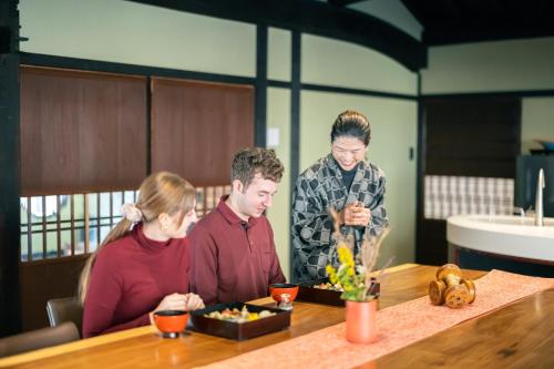 a group of people sitting at a table with food at NIPPONIA 美山鶴ヶ岡 Mountain Village in Ōno