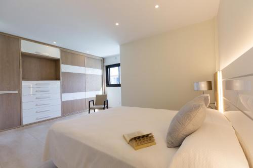 1 dormitorio con 1 cama blanca grande y 1 silla en Arguineguín Bay Apartments, en La Playa de Arguineguín
