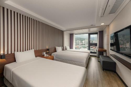 a hotel room with two beds and a large window at Hotel Air City Jeju in Jeju