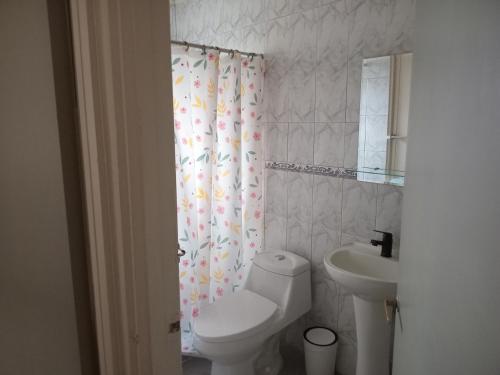 a bathroom with a toilet and a sink and a shower curtain at Don José in Los Molles