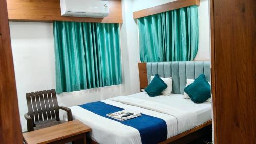 a bedroom with a bed with a chair and green curtains at Hotel New Vinayak in Ahmedabad