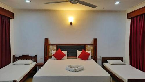 a bedroom with two beds with red pillows at Sea View Beach Hotel in Nilaveli