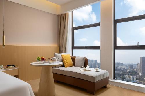 a hotel room with a couch and a table and windows at Surprise Hotel Chengdu in Chengdu