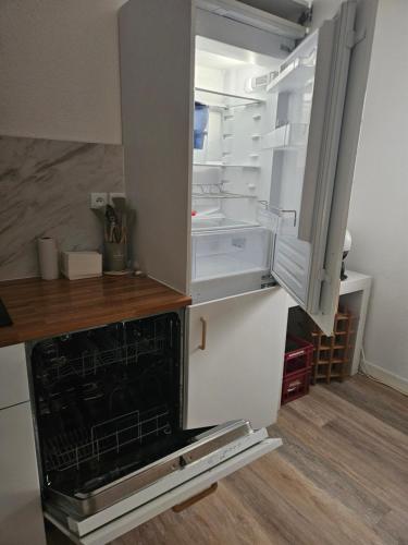 an empty refrigerator with its door open in a kitchen at Appartement dans résidence in Muret