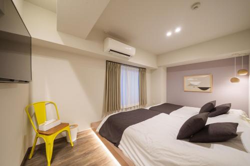 a bedroom with a bed with pillows and a yellow chair at PREMIER suite Shinjuku West 2F in Tokyo