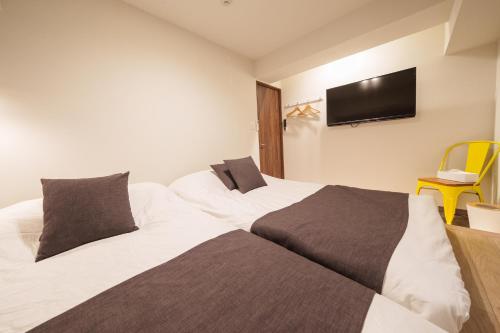 two beds in a room with a tv on the wall at PREMIER suite Shinjuku West 2F in Tokyo