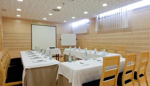 a conference room with white tables and chairs and a screen at Daniya Alicante in Alicante