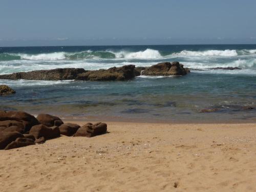 a sandy beach with rocks in the ocean at Sole's Leap in Scottburgh