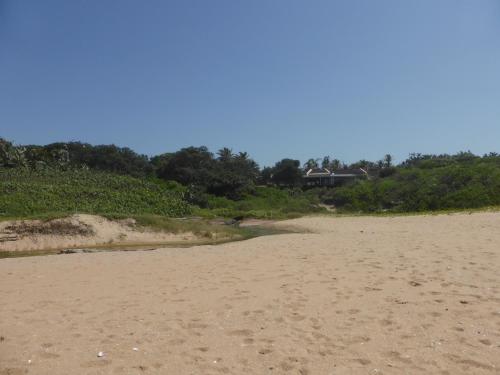 a sandy beach with a house in the background at Sole's Leap in Scottburgh