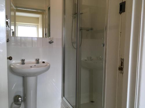 a white bathroom with a sink and a shower at Novar Arms Hotel in Evanton