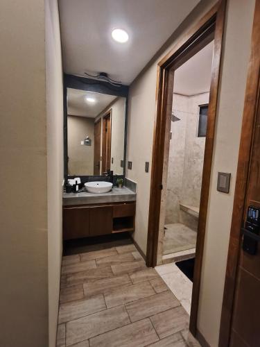 a bathroom with a sink and a tub and a mirror at Loft moderno y acogedor in Durango