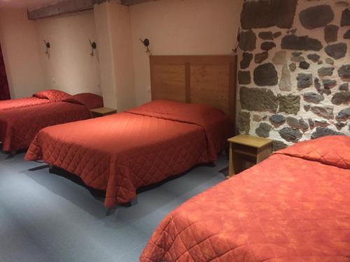 Habitación con 3 camas y pared de piedra. en Le Bilboquet, en Le Puy en Velay