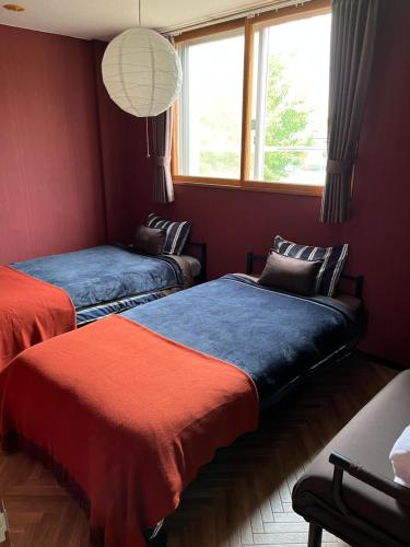 a bedroom with two beds and a window at Hokkaido Bed & Bagel in Eniwa