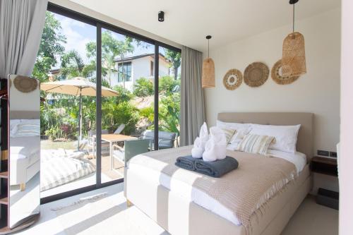 a bedroom with a bed and a view of a patio at Siam Mila Villas in Srithanu