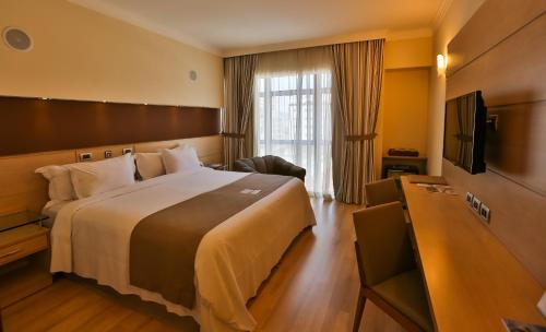 een hotelkamer met een groot bed en een televisie bij Bourbon Santos Convention Hotel in Santos