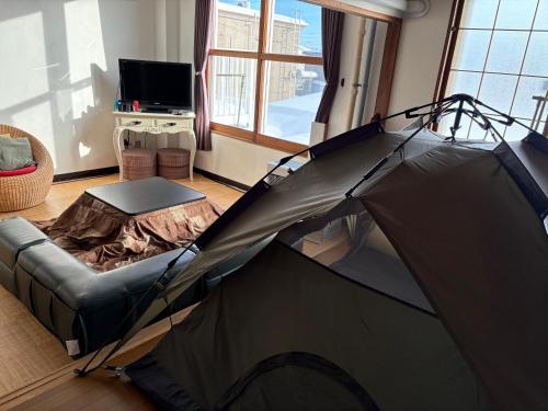 a tent in a room with a couch and a tv at Hokkaido Bed & Bagel in Eniwa