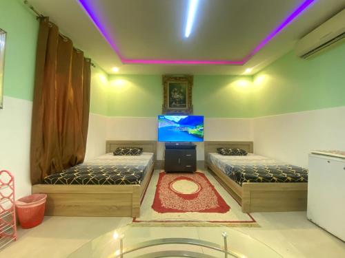 a room with two beds and a flat screen tv at Farmhouse One Bedroom Attached Bathroom in Al Rahba