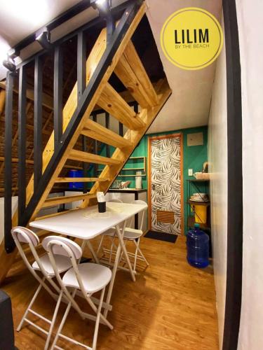a dining room with a table and chairs under a staircase at Duplex A- Seaside Haven Transient Inn at Caba, La Union in Caba
