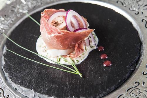 a dish with meat and onions on a black plate at Relais Casa Orter in Risano