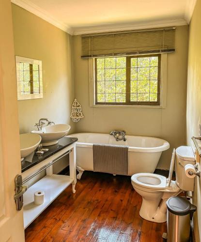 a bathroom with two sinks and a tub and a toilet at Magoebaskloof Getaway in Magoebaskloof