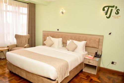 a bedroom with a large bed and a chair at TJ's Boutique Hotel in Eldoret