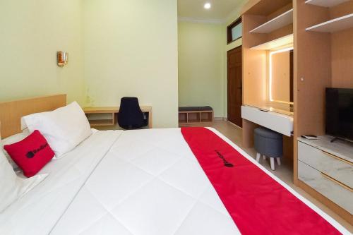a bedroom with a large white bed with a red blanket at RedDoorz Syariah at UIN Suska GuestHouse in Pekanbaru