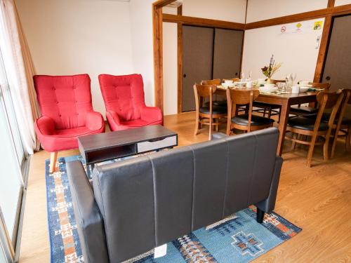 a dining room with a table and red chairs at Family Villa KASAMA in Kasama