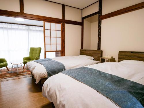 a bedroom with two beds and a chair and a table at Family Villa KASAMA in Kasama