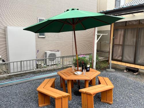 a table with a green umbrella and two benches at Family Villa KASAMA in Kasama