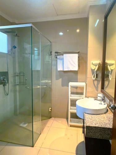 a bathroom with a glass shower and a sink at Kuta Town House Apartments in Kuta