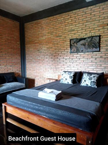 a bed in a room with a brick wall at Beachfront Guest House Pacitan in Tamperan
