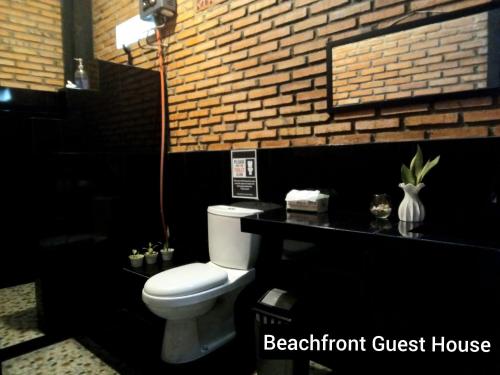 a bathroom with a toilet and a brick wall at Beachfront Guest House Pacitan in Tamperan