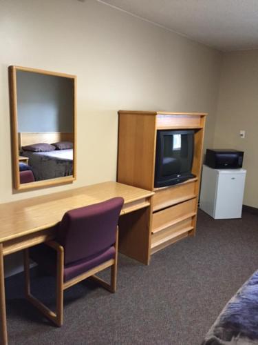 Habitación con escritorio, TV y espejo. en Nights Inn Motel, en Thunder Bay