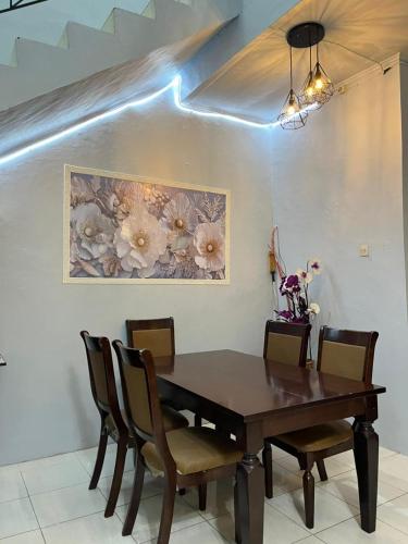 a dining room table with chairs and a painting on the wall at Villa Bukit Asri Berastagi in Berastagi