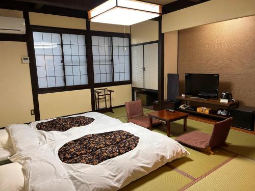 a bedroom with a large bed and a tv at Iwamura Sanso -Castle Ryokan- in Ena